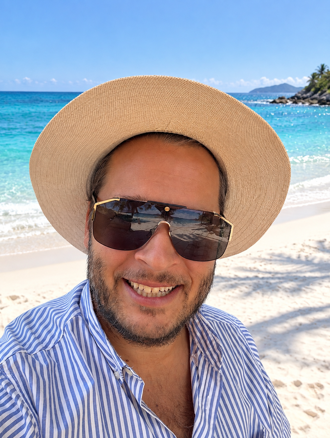 Roman mit Strohhut und Sonnenbrille am weißen Sandstrand